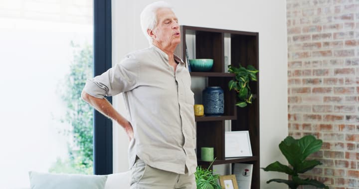 an elderly man stretches his painful back