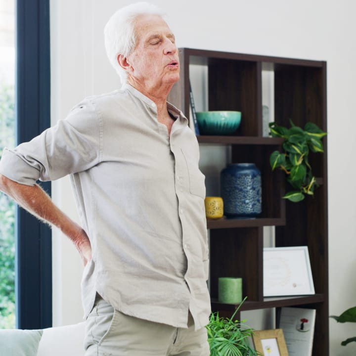 an elderly man stretches his painful back