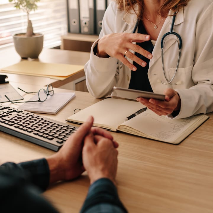 A doctor reviews information on a tablet with a patient during an office visit