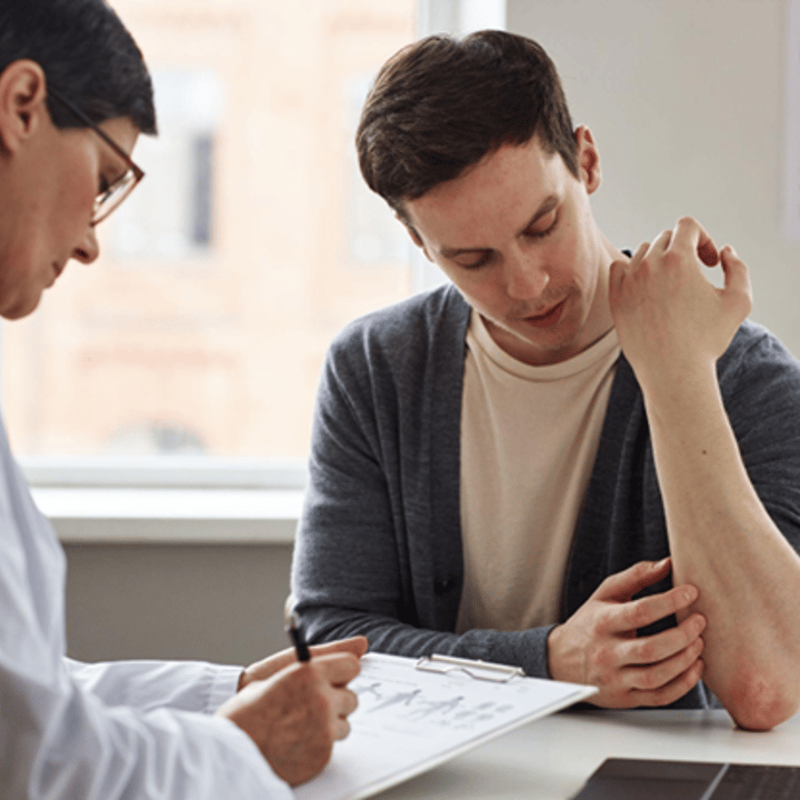 A young man showing a skin rash to a doctor