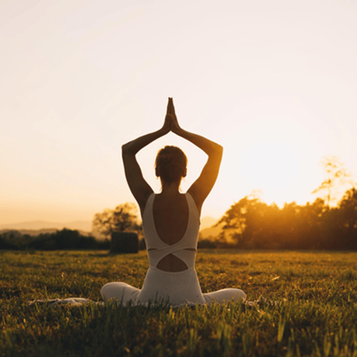 Young woman practicing yoga outdoors at sunrise