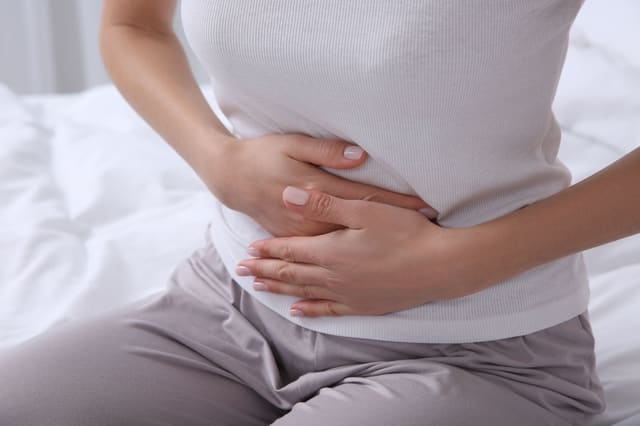a close up for a woman holding her hands to her stomach