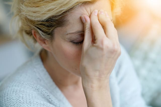 a middle-aged woman dealing with a migraine