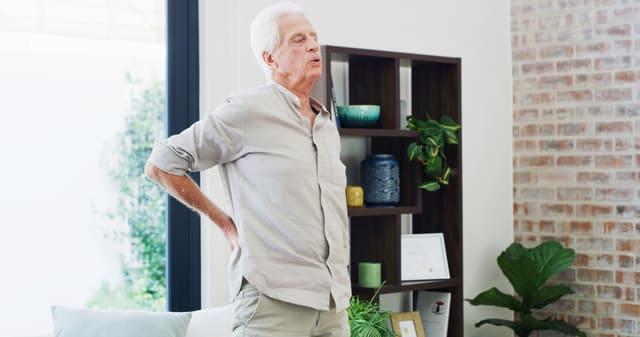 an elderly man stretches his painful back