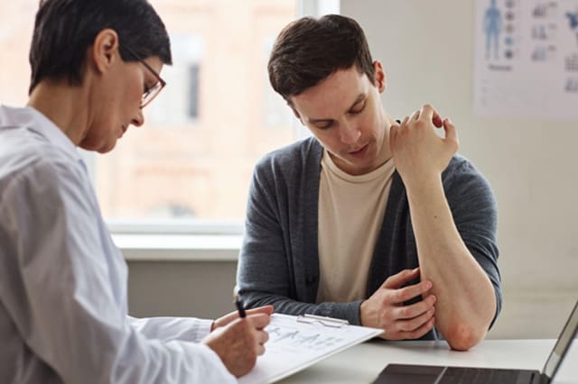A young man showing a skin rash to a doctor