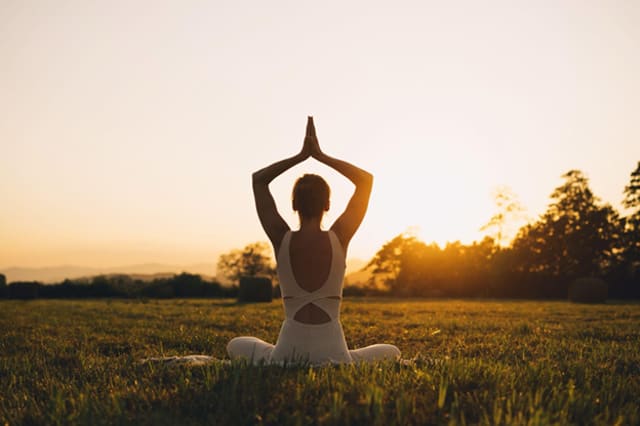 Young woman practicing yoga outdoors at sunrise