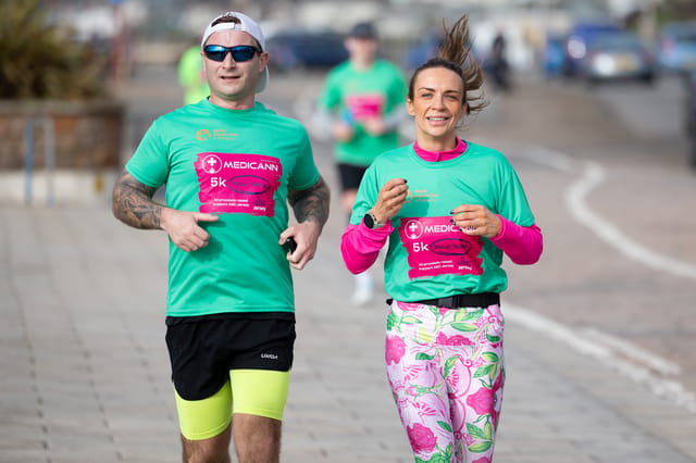 Two participants running in green Medicann event shirts.